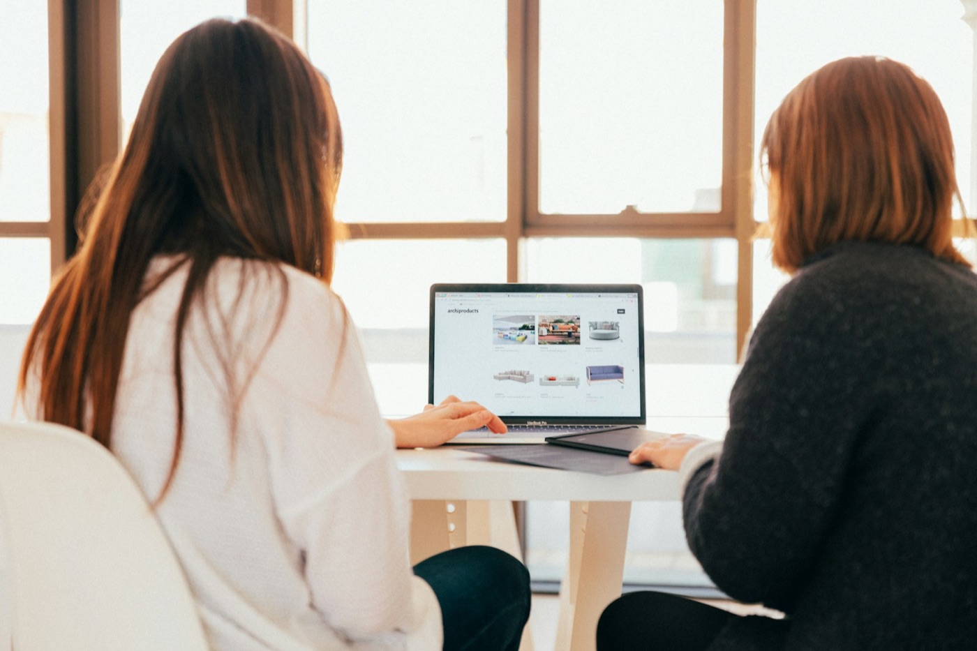 Two colleagues working through a problem together at a laptop.